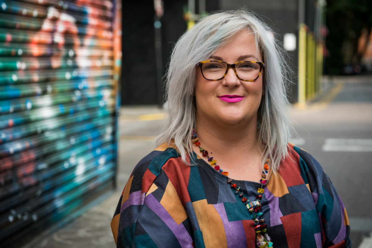 Emily Yates smiling in front of bright graffiti