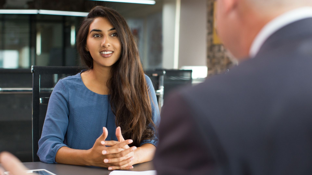 Standard reasonable adjustments - a dark haired woman sits across a desk from a man in a suit, only his back is visible.