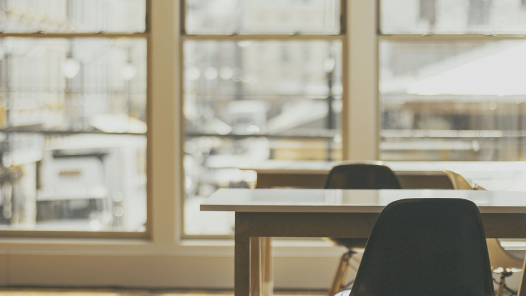 two office chairs and a desk positioned next to a large bright window