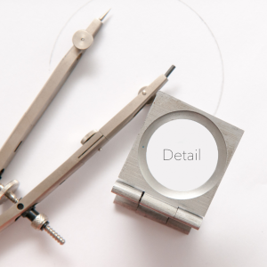 Magnifying glass with 'detail' inside and two graphic design pencils