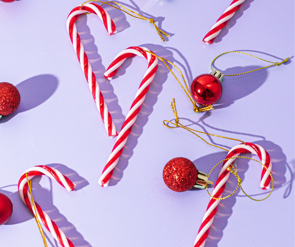 Inclusive christmas: a series of red and white candy canes on a purple background. There are christmas tree baubles too